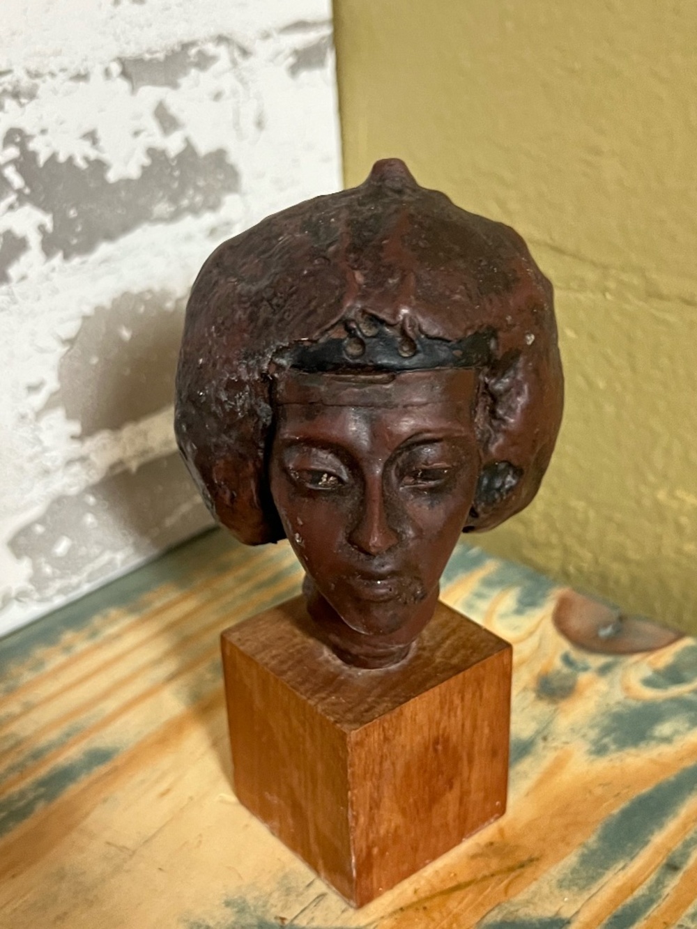 Hand-carved Resin bust of a woman's head mounted on a square wooden block.